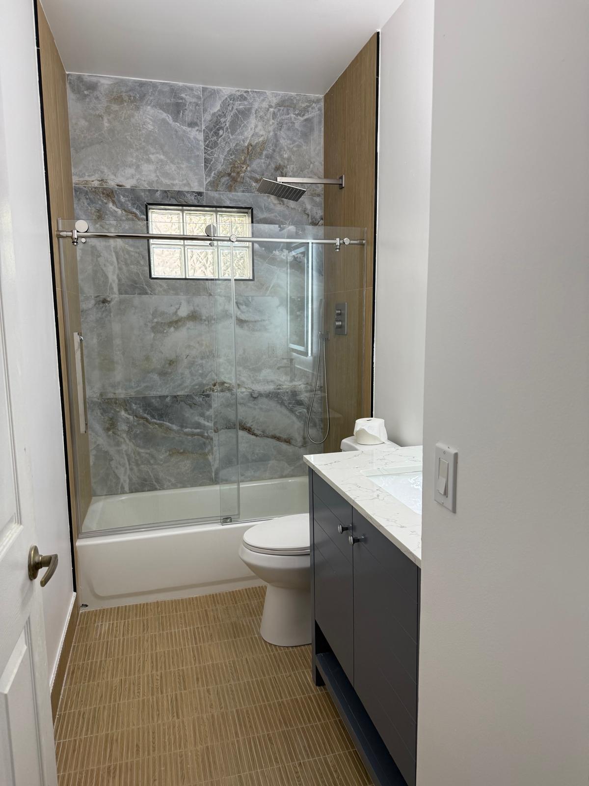 Grey marble tub-shower combo with frameless glass door