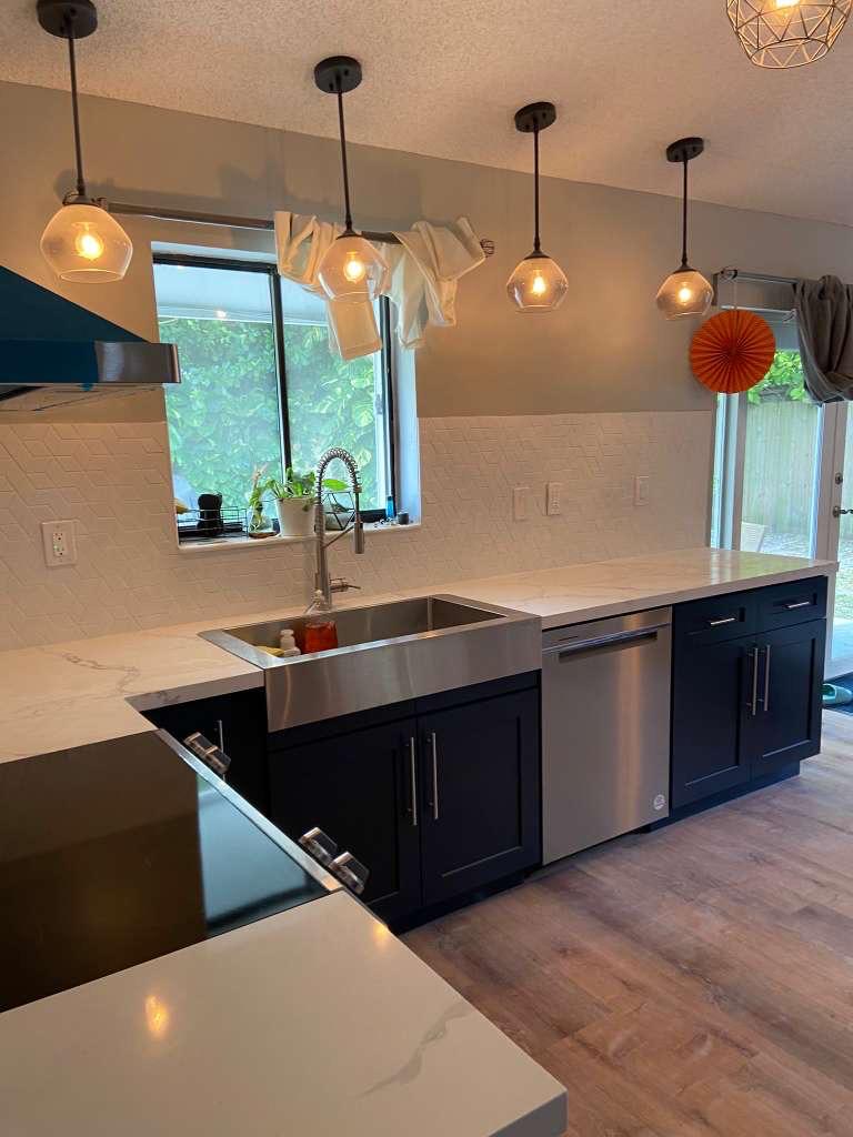 Navy island kitchen with farmhouse sink and glass pendant lights