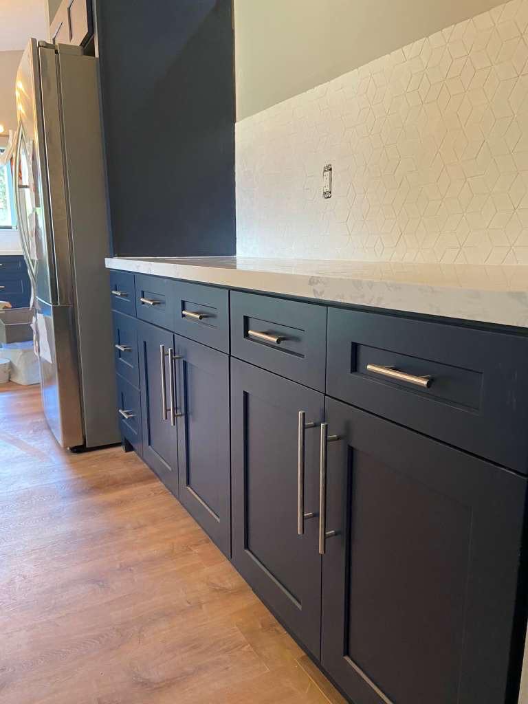 Navy shaker base cabinetry with brushed nickel pulls and geometric backsplash