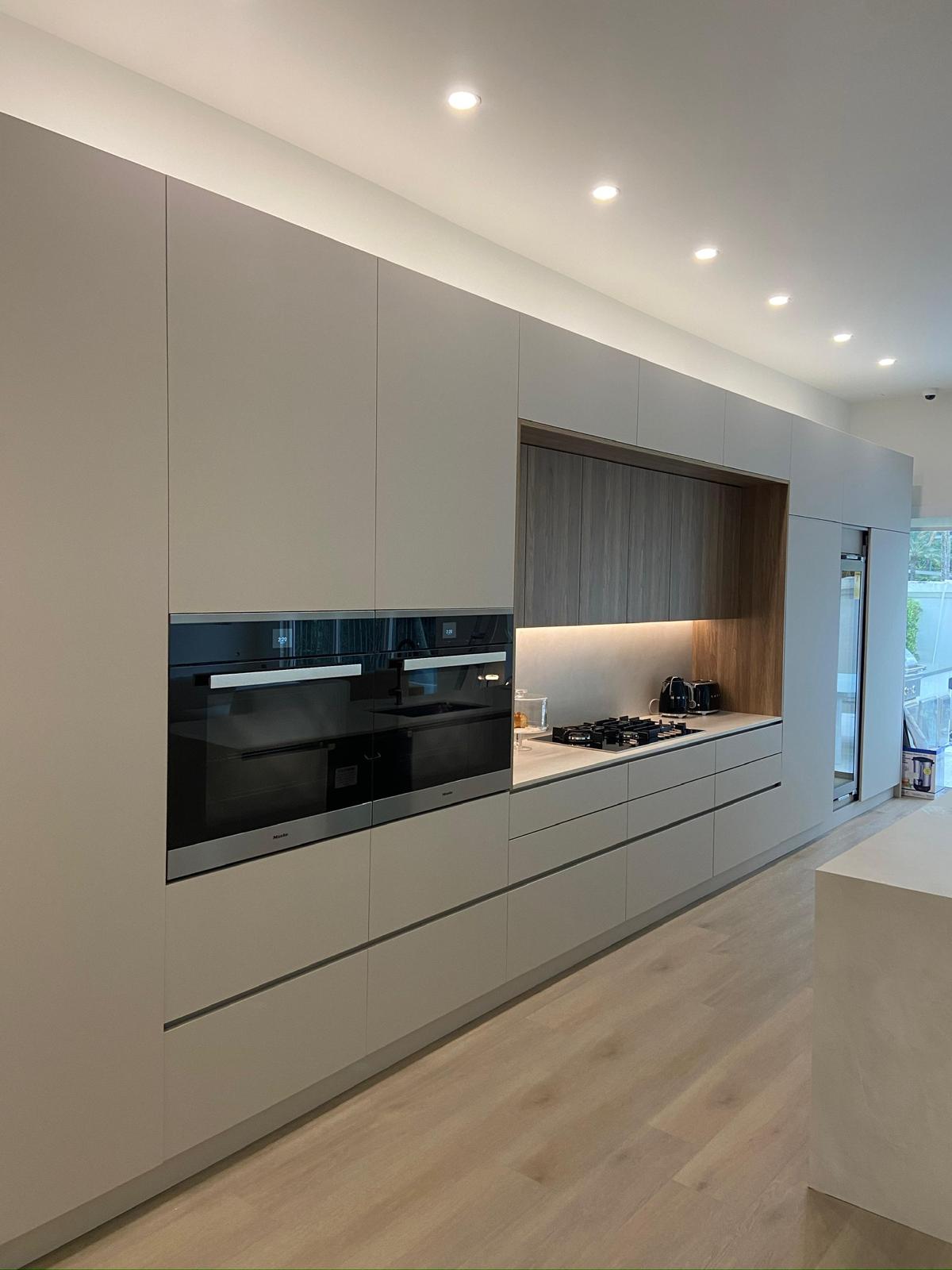 Minimalist handle-less kitchen with Miele appliances and walnut niche