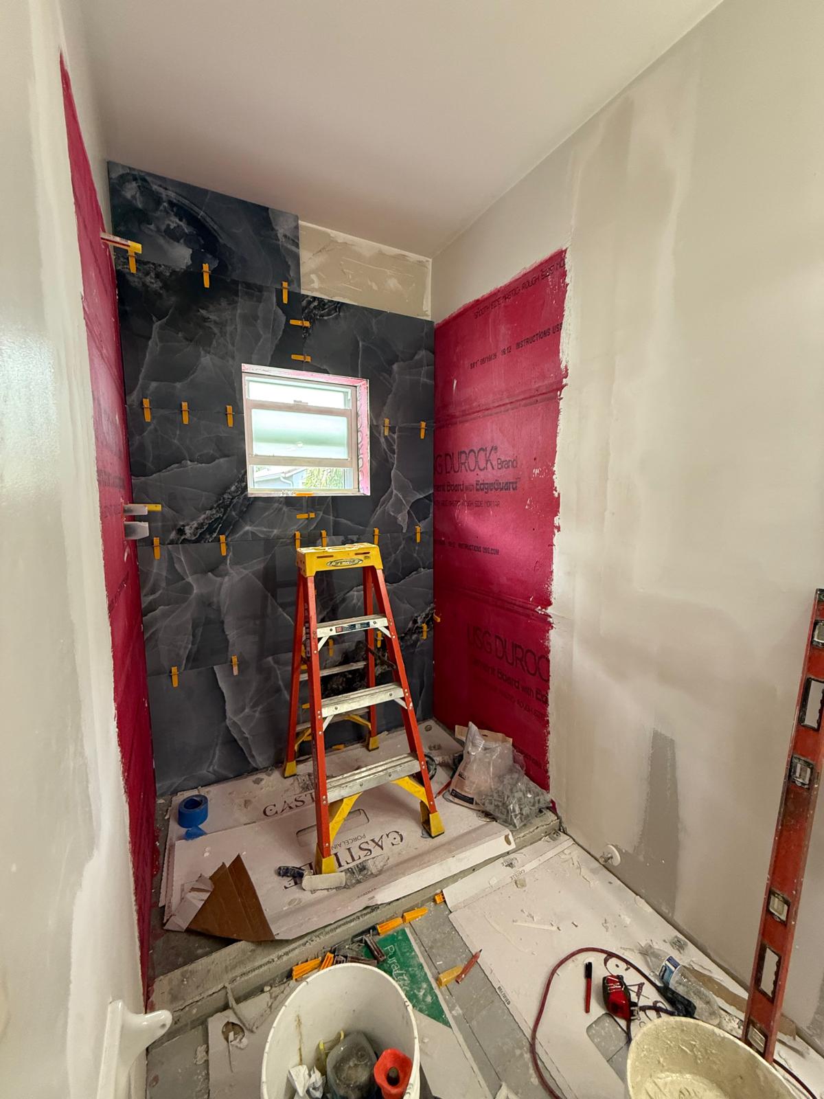 Bathroom in progress — black marble shower tile install with leveling clips