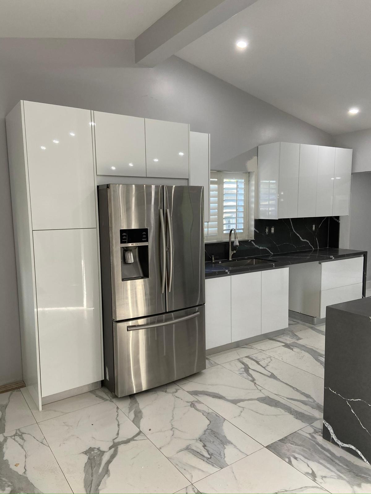 High-gloss white kitchen with black quartz counters and marble floor