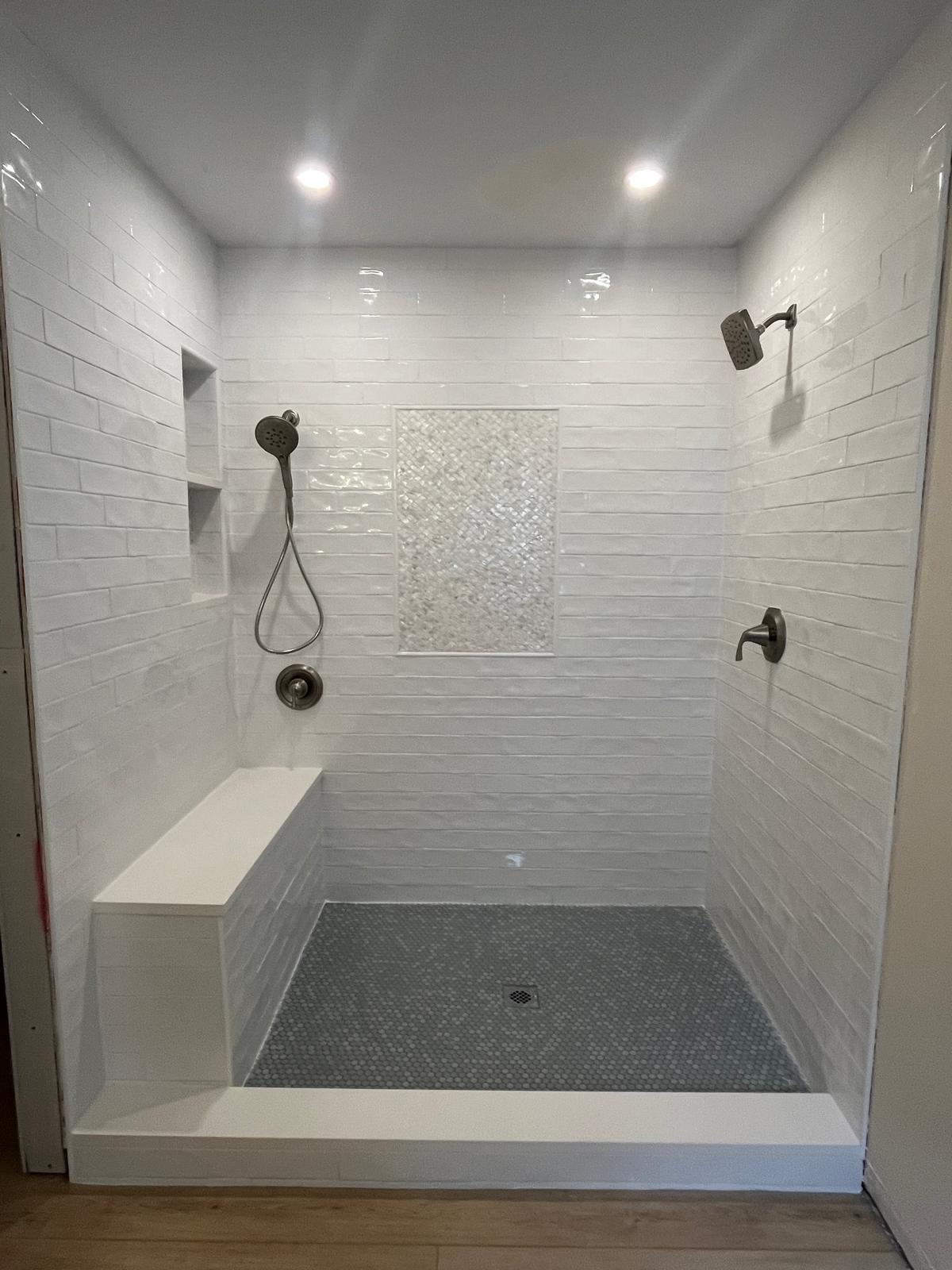 White subway tile walk-in shower with built-in bench and niche