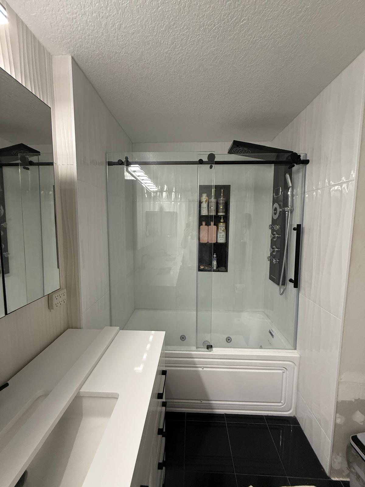 Jetted tub with black-framed glass enclosure and rainfall shower